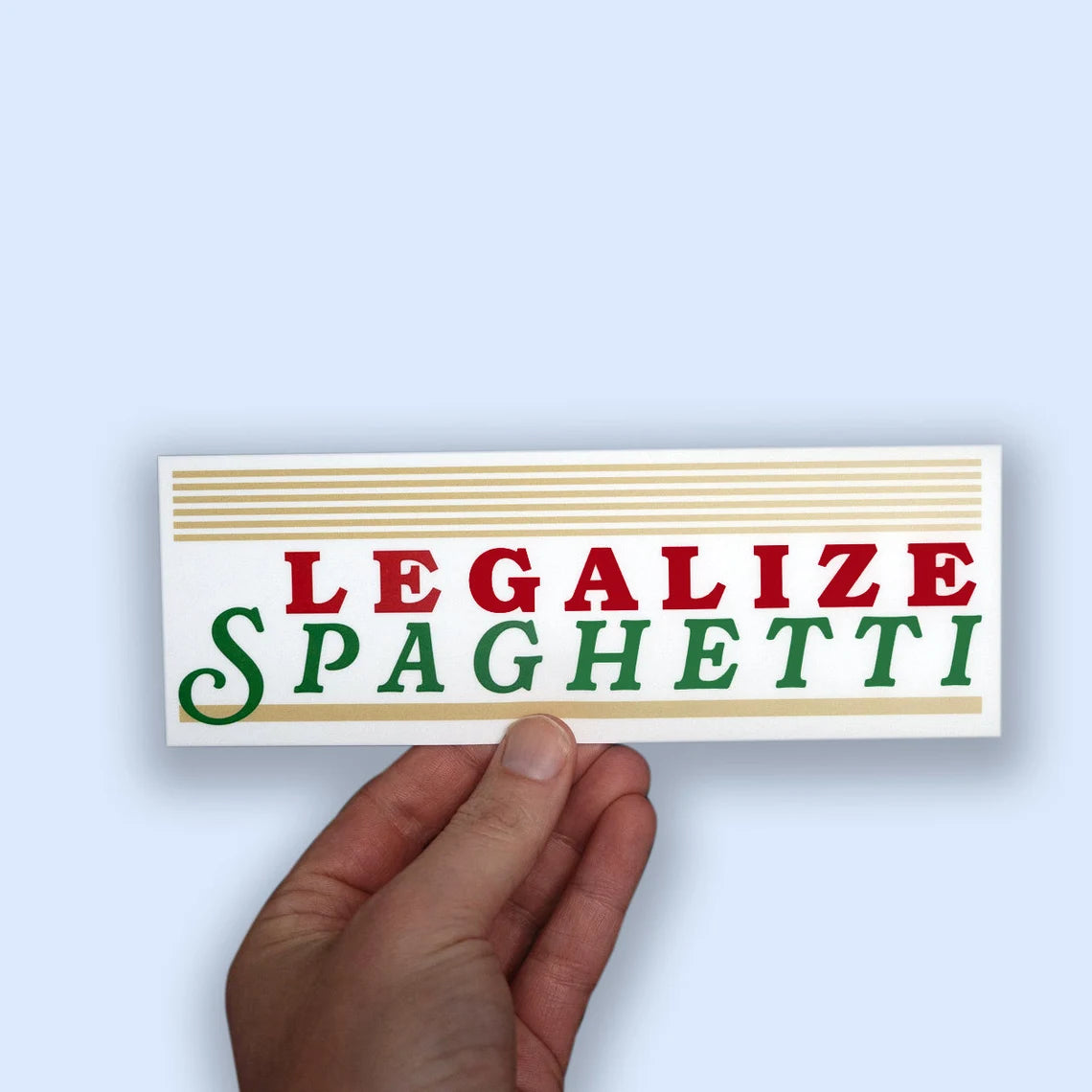 Hand holding a sticker with 'LEGALIZE SPAGHETTI' sticker on a light blue background