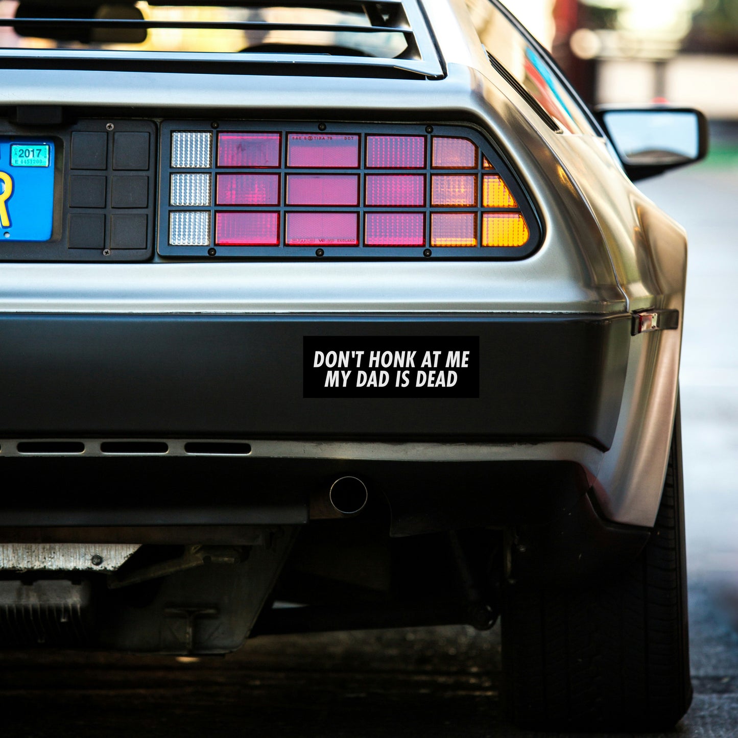 Back of a car with a 'Don't Honk at Me My Dad is Dead' bumper sticker.