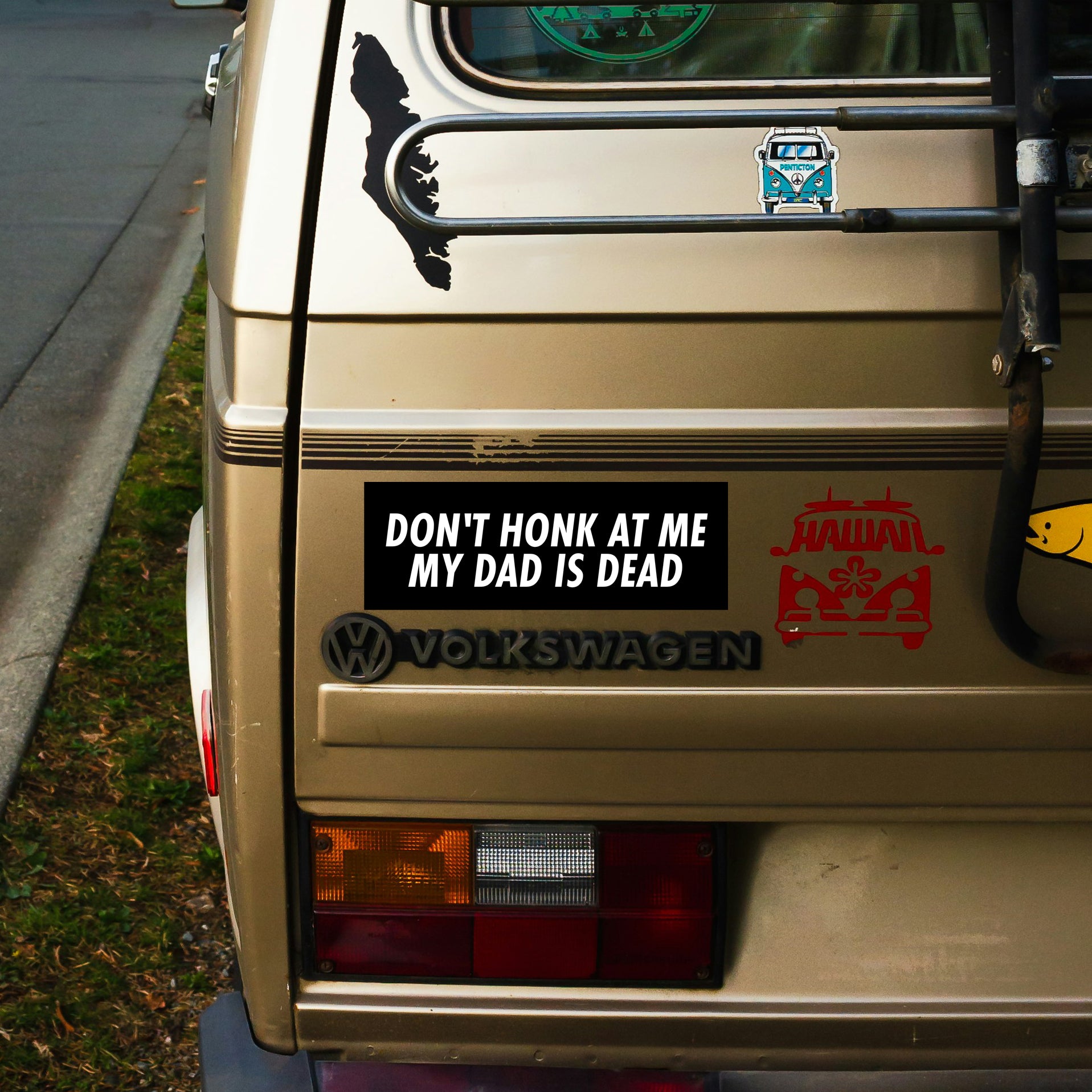 Back of a Volkswagen van with various stickers, including one that reads 'Don't Honk at Me My Dad is Dead'.